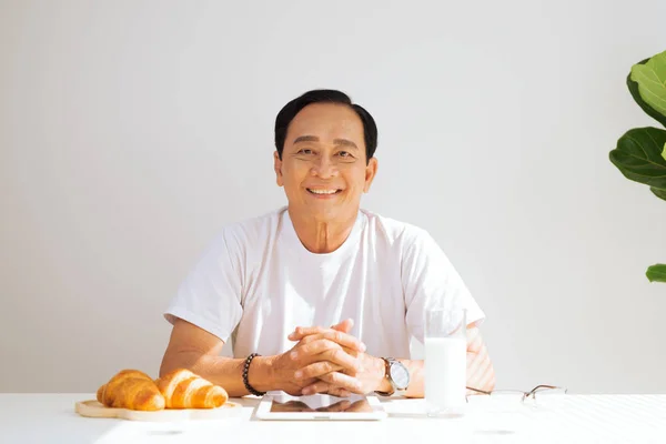 Feliz Pareja Ancianos Desayunando Croissant Casa Bebiendo Leche Tocando Tableta — Foto de Stock