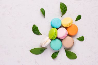 Bahar kavramı macaroons ve yeşil yaprakları ile. Üstten Görünüm