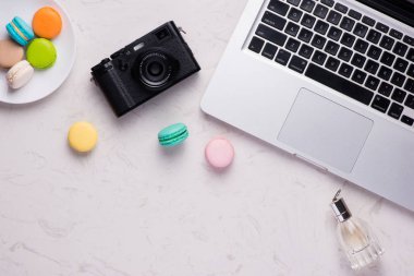 Renkli macaroons, kamera ve dizüstü bilgisayar ile beyaz Masası