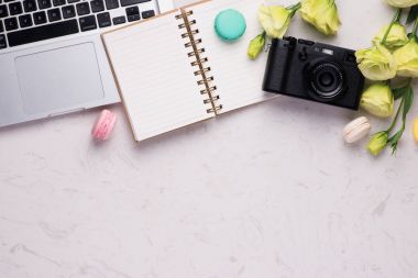 Renkli macaroons, kamera ve dizüstü bilgisayar ile beyaz Masası