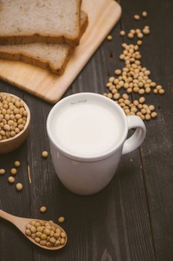 Soya süt ve soya fasulyesi ahşap arka plan üzerinde cam