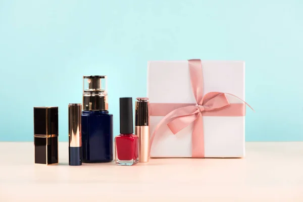 Makeup cosmetics with gift box on wooden table.