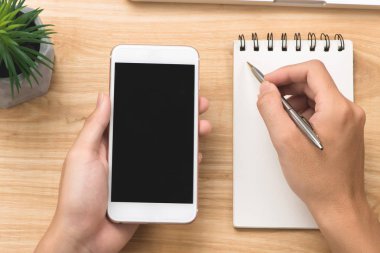 Telefon kullanarak ele yakın çekim. Smartphone şablon ofis masasında sahte.