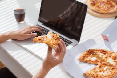 Asya bir adamın masasında çalışırken yemek pizza ile Resim kırpılmış.