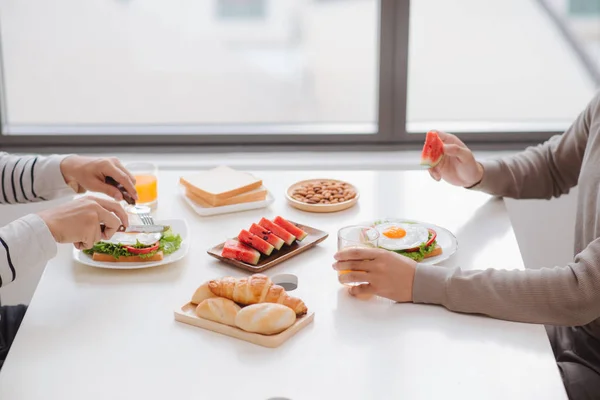 Two male friends eating breakfast at home in morning