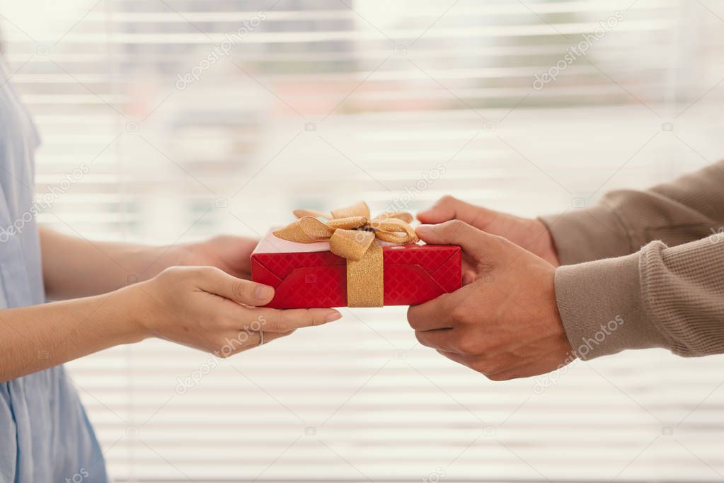 Couple in love. Male and female hands holding red gift box