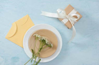 Tet Bayramı tatil kavramı. Plaka, hediye kutusu ve çiçekler ile mavi tabloda sarı zarf.