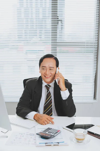 Handsome mature businessman in classic suit talking on mobile phone working in office