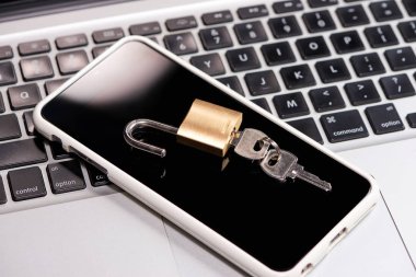Smartphone ve asma kilit bir dizüstü bilgisayar klavye üzerinde yalan