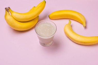 Taze meyve yüzlü cam ve muz üzerinde pembe arka plan yaptı
