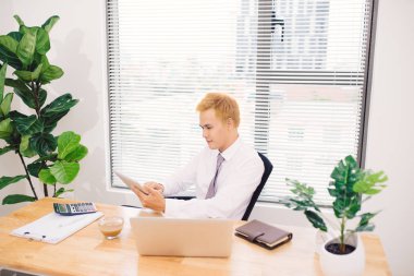 Masa başında oturan dijital tablet kullanarak iş adamı
