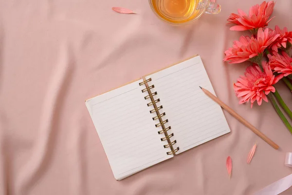 ピンクの布の上の鉛筆 紅茶のカップを持つ空白のノートブックを開く — ストック写真