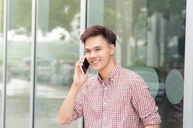 Office dışı smartphone ayakta konuşurken kendinden emin Asyalı adam