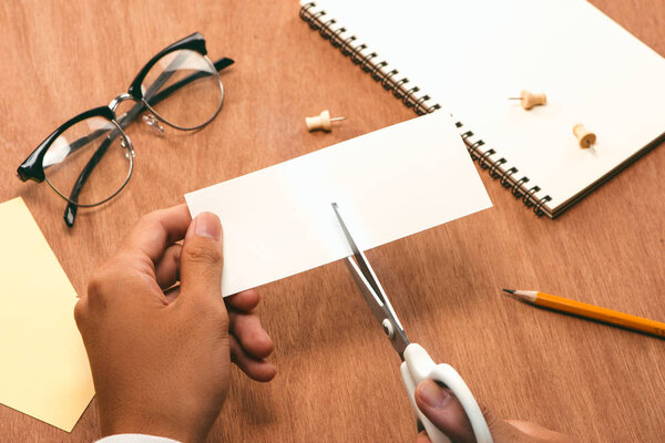 Male hands cutting piece of paper by scissors