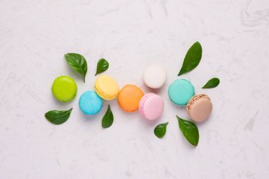 Bahar kavramı macaroons ve yeşil yaprakları ile. Üstten Görünüm