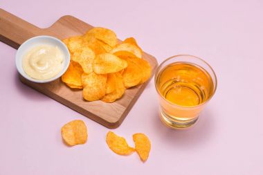 Peynir ve soğan patates cipsi ile alkolsüz içecek pembe bir arka plan üzerinde.