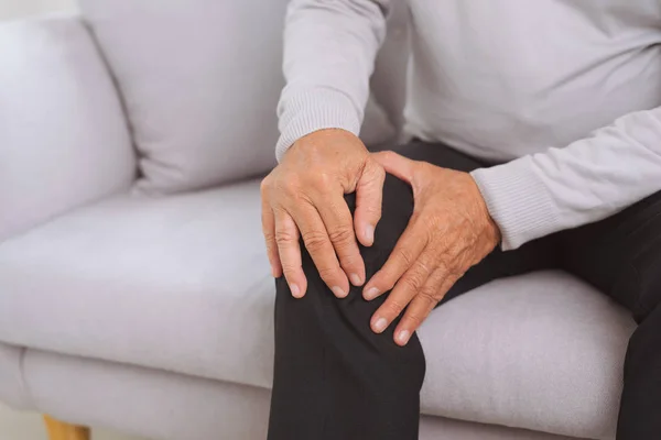Senior Man Zittend Bank Huiskamer Zijn Knie Aan Raken Door — Stockfoto