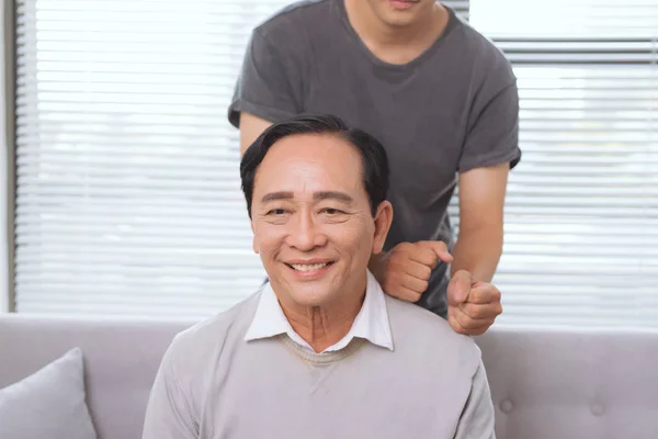 Son Massaging Father Shoulder Sitting Sofa — Stock Photo, Image