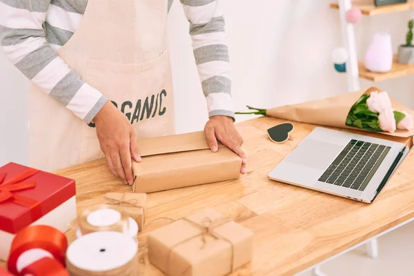 man wrapping purchase working in shop of gifts, crop