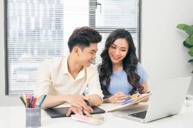 İki rahat tasarımcıları ofis masasında otururken dizüstü bilgisayar ile çalışma gülümseyen