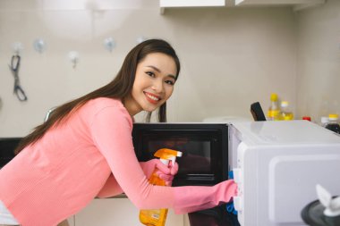 Young asian woman cleaning kitchen with detergent spray.