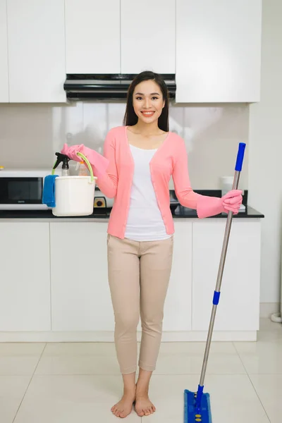 愉快的亚洲妇女与拖把清洁地板在厨房里 — 图库照片