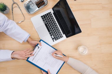 Steteskop, tıbbi reçete formu, sağlık muayenesi sonuçlarını tartışan doktor ve hastanın geçmişine karşıdır.