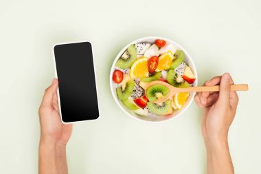 Smartphone ile lezzetli bir yaz meyve zevk adam görünümünü top, kırpma