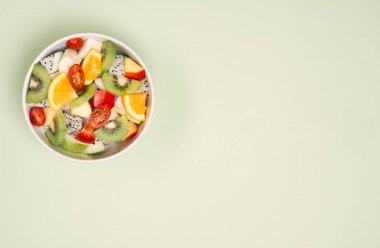 Tahta arka planda bir kase sağlıklı taze meyve salatası. Üst görünüm.