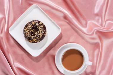 Flat lay of breakfast with donut and black coffee.