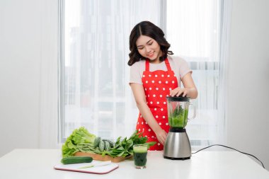 Genç Asyalı kadın evde mutfakta yeşil Detoks smoothie yapmak.