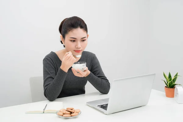 Hermosa Asiático Negocios Mujer Comer Yogur Sonriendo Mientras Sentado Trabajo — Foto de Stock