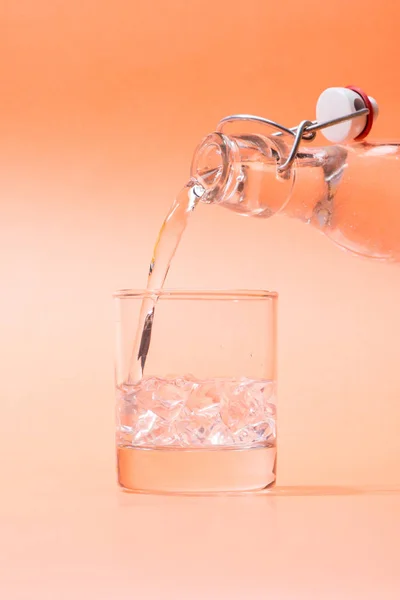 Verter Agua Botella Vaso Sobre Fondo Naranja — Foto de Stock