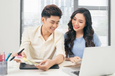 İki rahat tasarımcıları ofis masasında otururken dizüstü bilgisayar ile çalışma gülümseyen