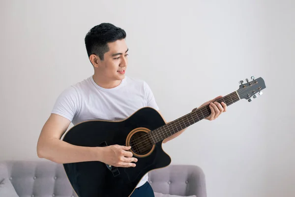 Asya Yakışıklı Evde Kanepede Gitar Çalmaya — Stok fotoğraf