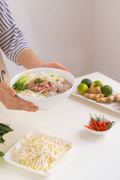 Female chef prepare traditional Vietnamese soup Pho bo with herbs, meat, rice noodles — Stock Image Female Chef Prepare Traditional Vietnamese Soup Pho Herbs Meat Rice Royalty Free Stock Photos