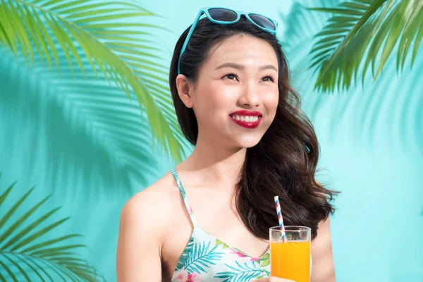 Genç Asyalı kadın içecekler suyu bardaktan mavi renkli arka plan üzerinde