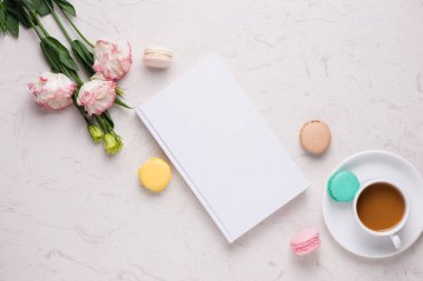 Çay saati düz yatıyordu. Fincan kahve ve beyaz arka plan üzerinde renkli macaroons