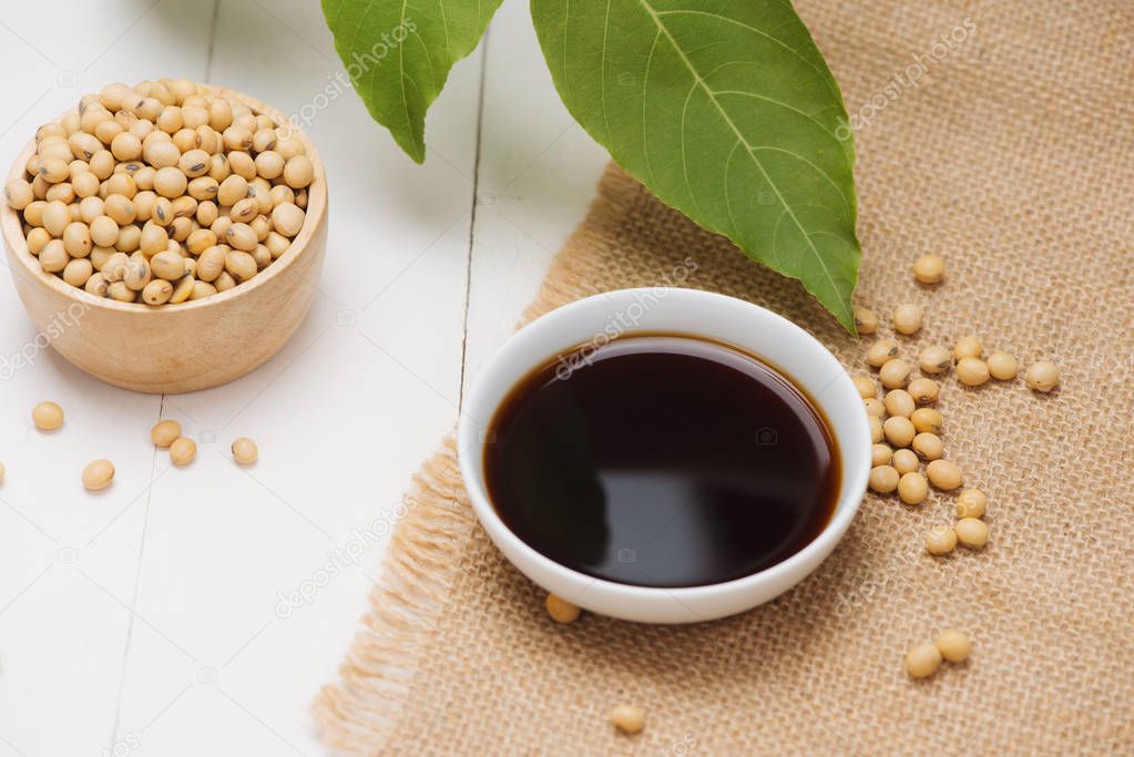 Soy sauce in bowl and soy beans on wooden table