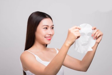 Güzel Asyalı kadın yüzüne kağıt örtü takıyor. Beyaz arka plan..