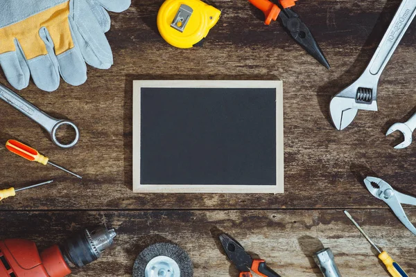 Labor day. Construction tools and blank chalkboard on wooden background with copy space