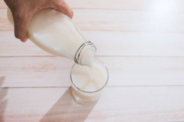 el ahşap bir masa üzerinde bir bardak içine dökülen süt