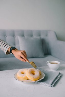 Yemek ve ekmek, şeker Toppings ile lezzetli taze ve tatlı çörek üzerinde beyaz çanak tutan el.