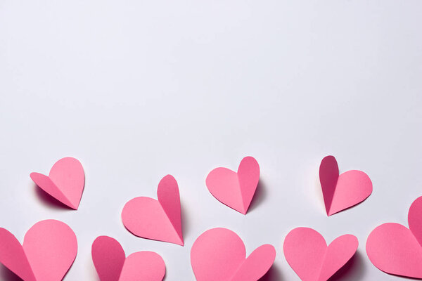 Розовые бумажные сердца на белом бумажном фоне
