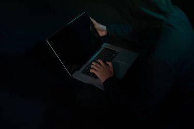 Hacker karanlık bir defter önünde oturan hoody. Bilgisayar gizlilik saldırı