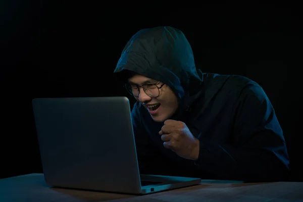 Hacker in a dark hoody sitting in front of a notebook. Computer privacy attack