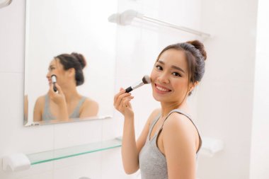 Onu banyoda makyaj allık uygulayarak güzel kadın