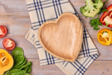 Taze organik sebze ve ahşap kalp disk kopyalama alanı natürmort ile ahşap zemin üzerinde içerir