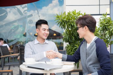 anlaşma imzalamaya el sıkışan iki iş adamları