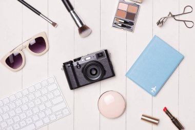 Women cosmetics and fashion items on table with camera and passport. Top view clipart